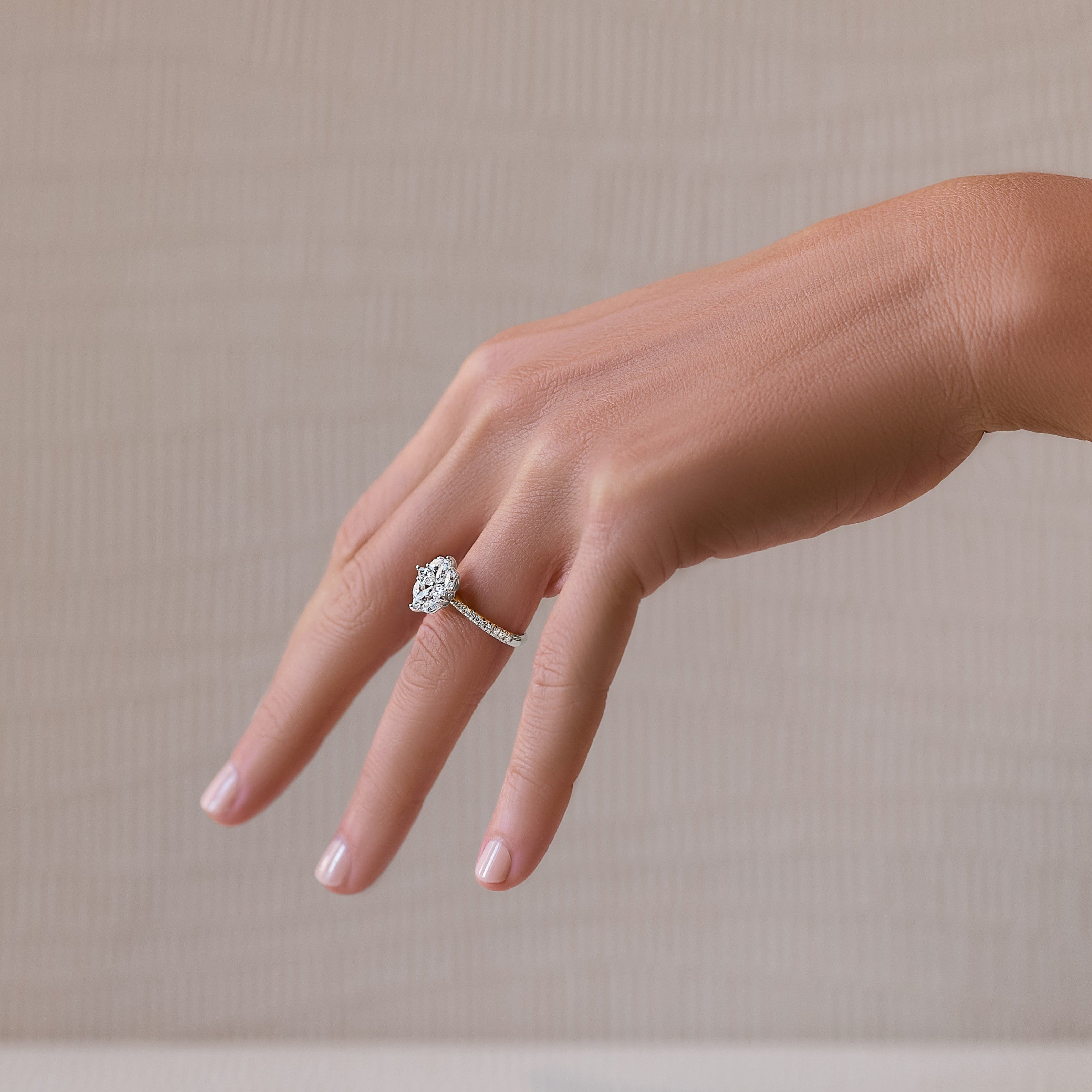 A hand showcasing a white gold geometric floral ring with a centerpiece bloom and diamond accents.