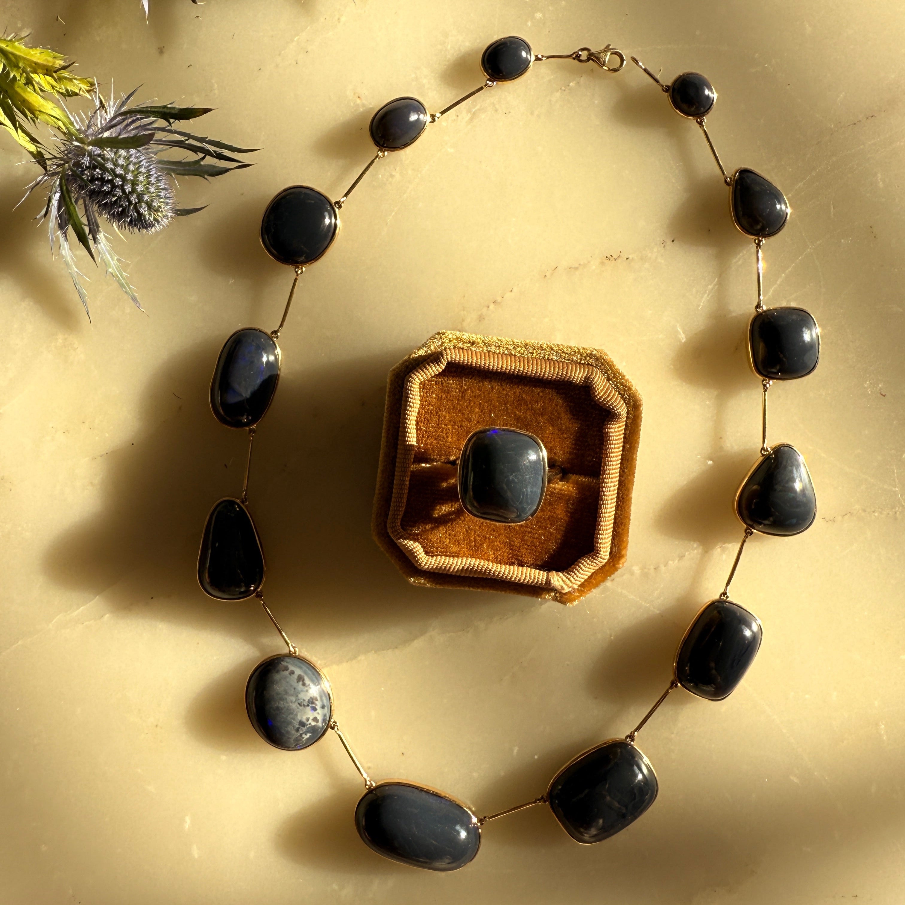 Necklace with black stones and a small box on a beige background