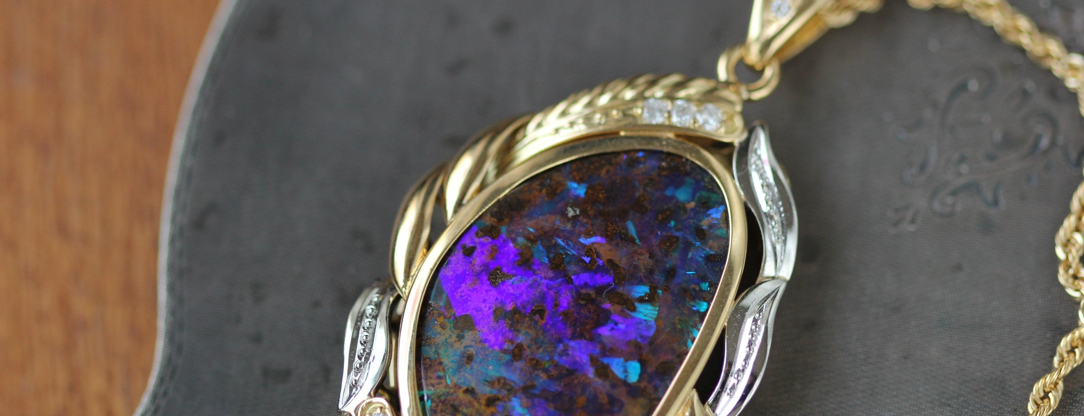 Opal pendant with gold setting on a dark stone surface