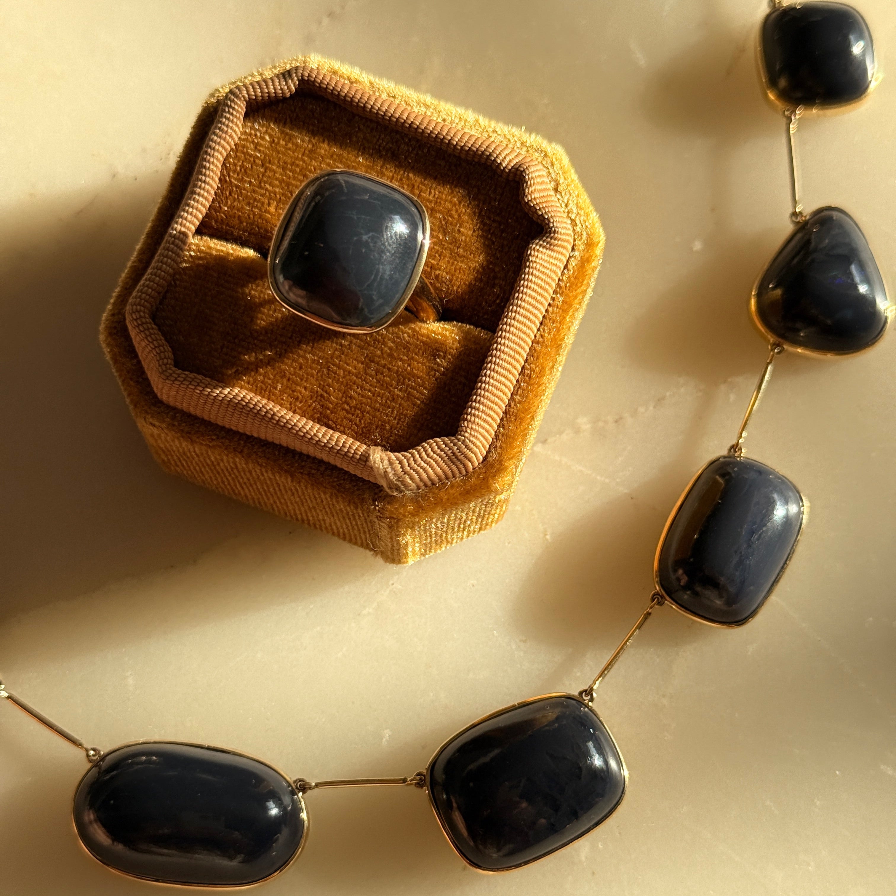 Necklace with black stones and gold accents on a beige background