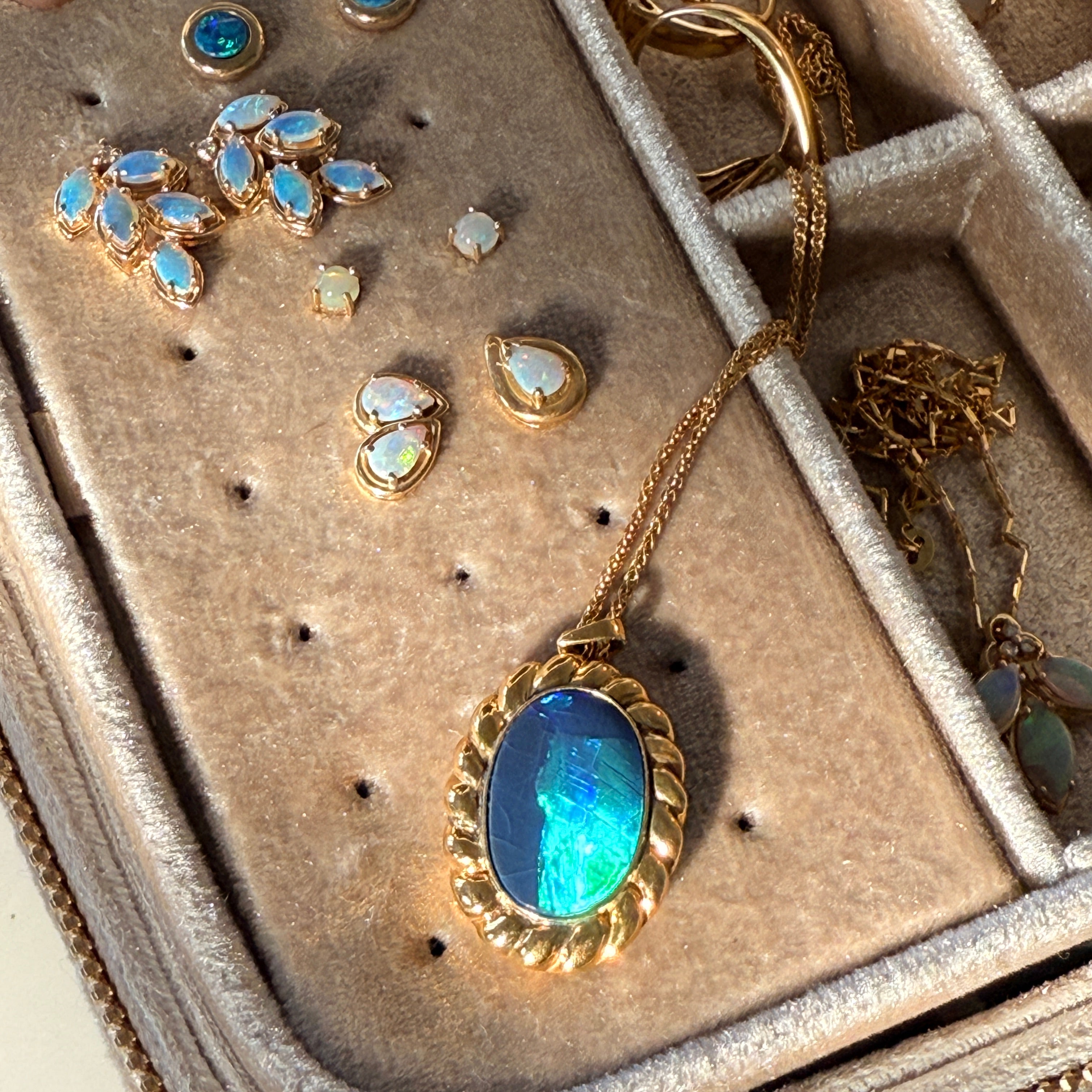 Gold jewelry set with opal stones on a textured surface