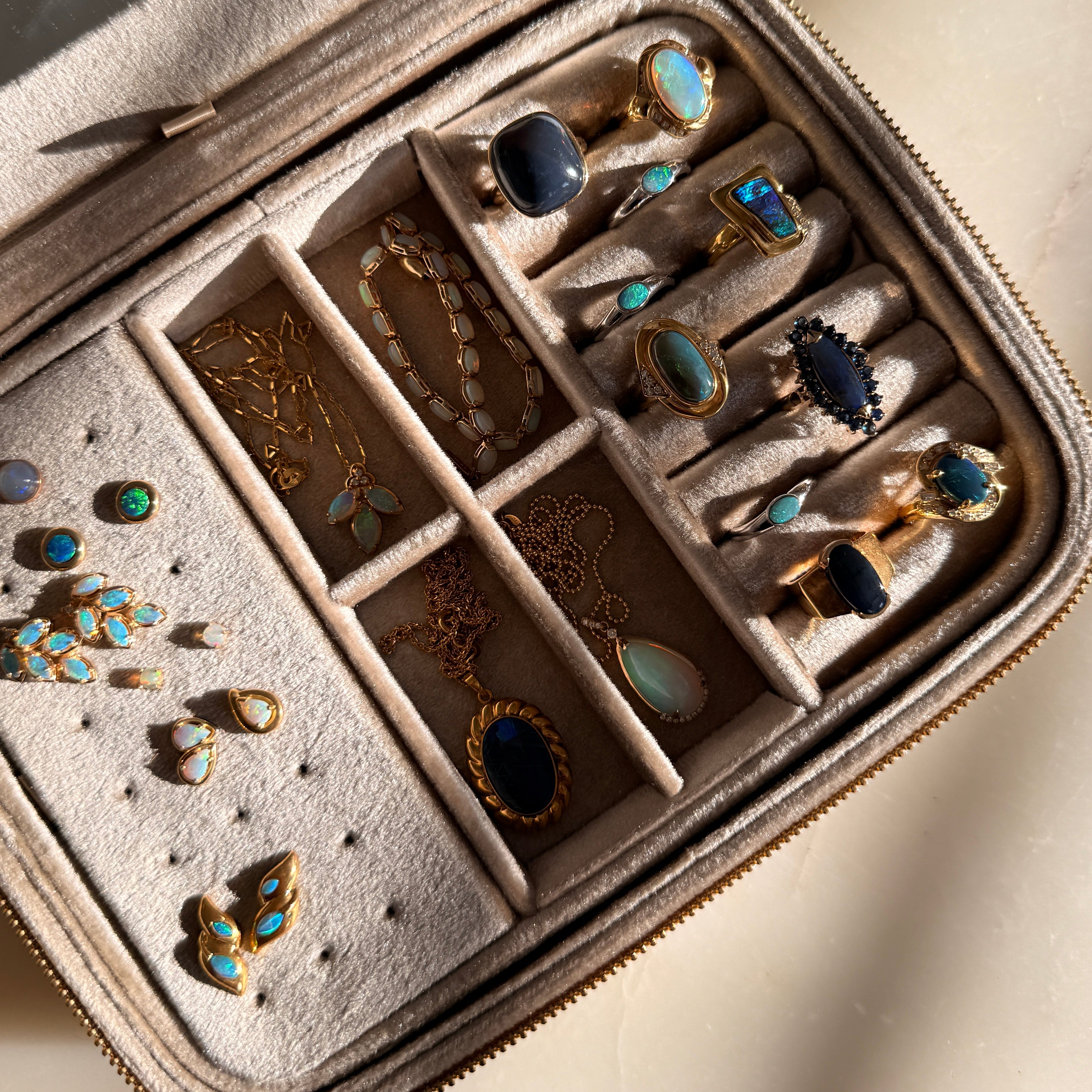 Jewelry set in a beige jewelry case with various opal rings and earrings.