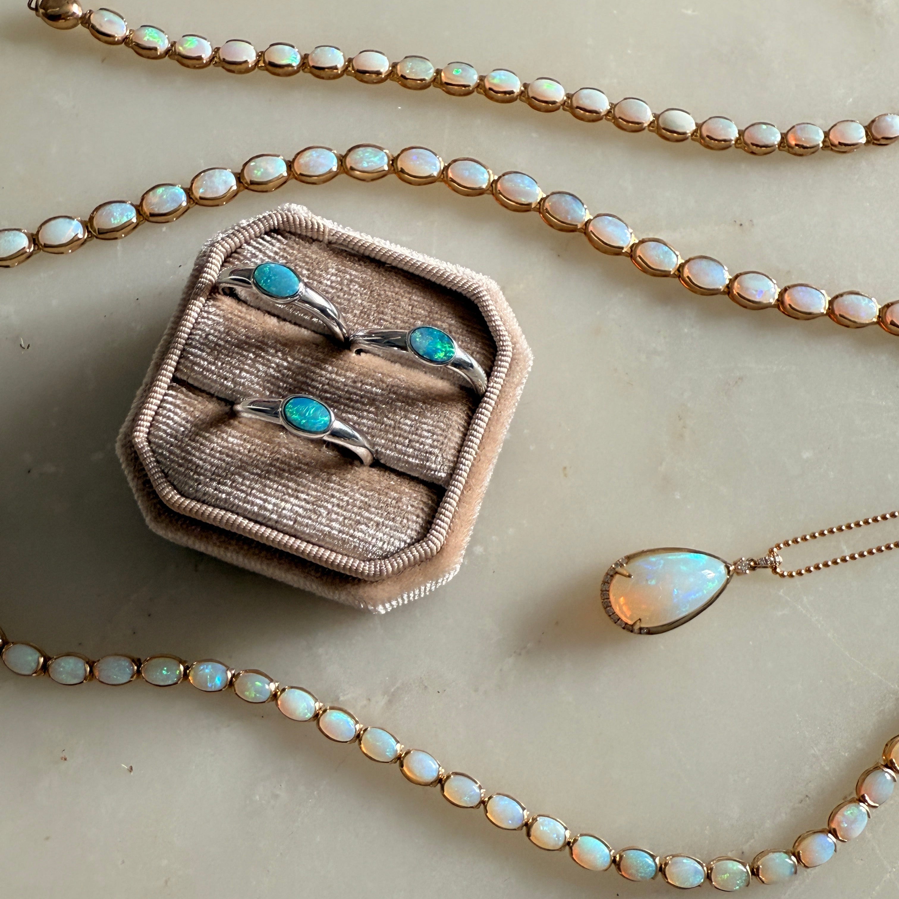 Necklace with opal beads and a pendant, displayed on a neutral background