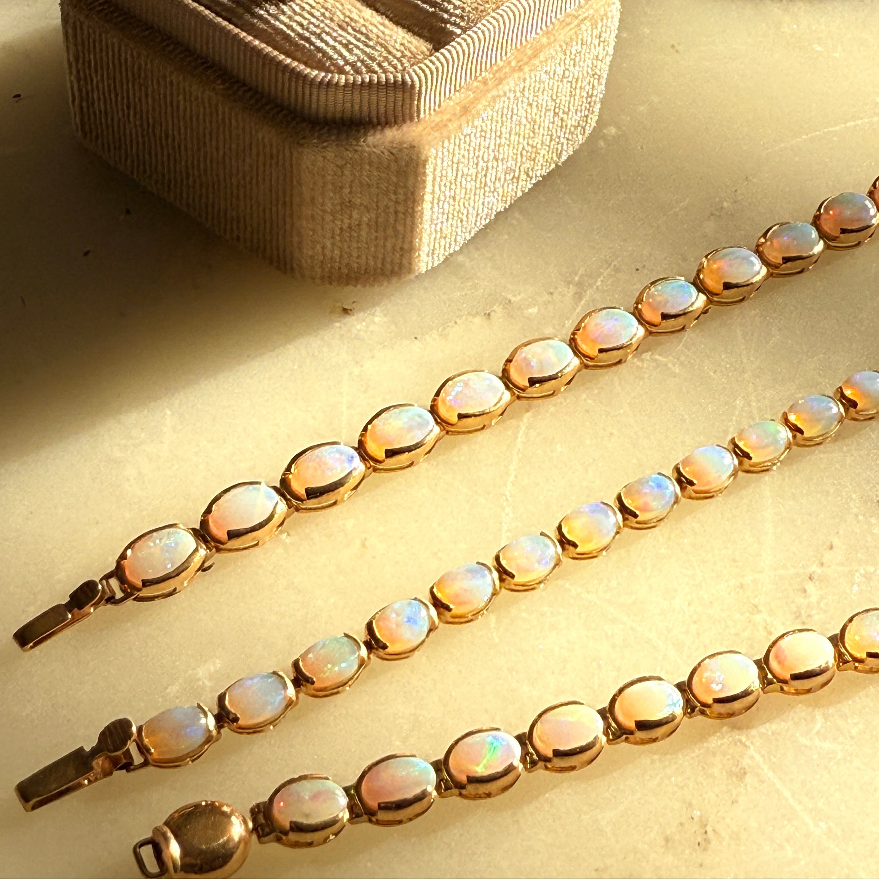 Opal necklace and earrings on a textured surface with a jewelry box.